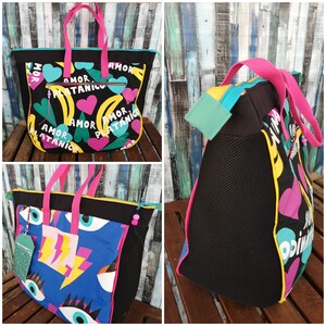 May include: Two black tote bags with colourful designs. One bag has a design of hearts, bananas, and the words "Amor Platanico". The other bag has a design of eyes, lightning bolts, and the words "Amor Platanico".