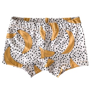 Pode incluir: Shorts de algod&atilde;o branco com estampa de bananas amarelas e bolinhas pretas.