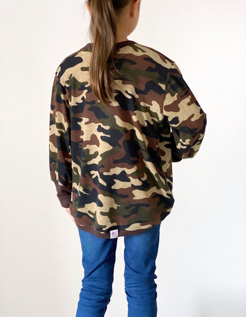 May include: A long-sleeved shirt with a camouflage pattern in shades of brown, green, and beige. The shirt has a crew neck and is made of a soft, comfortable fabric.