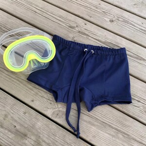 Pode incluir: Cal&ccedil;&atilde;o de banho azul marinho com cord&atilde;o de ajuste na cintura. O cal&ccedil;&atilde;o &eacute; feito de um tecido macio e de secagem r&aacute;pida.