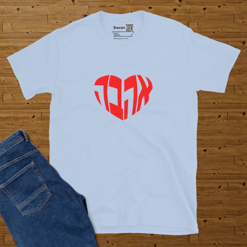 Light blue t-shirt spread on a brown parquet with blue jeans on left.  Design the Hebrew word ahava in red heart shape. Approx total design size 7 x 6.4 inches.
