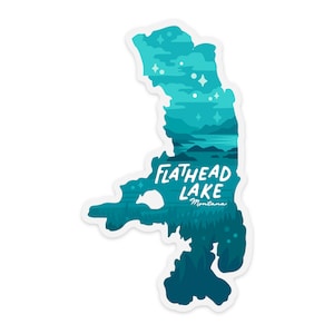 May include: A die-cut sticker in the shape of Flathead Lake, Montana. The sticker features a layered illustration in shades of teal and blue, with the lake's name in white script. The design includes trees, mountains, and stars.