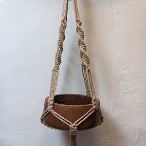 Suporte para plantas em macramê com nó torcido de juta, estilo rústico, ideal para presente de boas-vindas ou para uso interno ou externo.