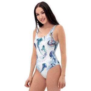 Op de afbeelding: Een wit badpak met een aquarelprint van kwallen in tinten blauw, paars en groen.