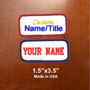 May include: Two white iron-on patches with red, blue, and yellow embroidered text. The top patch says "Custom Name/Title". The bottom patch says "YOUR NAME". The patches are 1.5 inches by 3.5 inches and are made in the USA.
