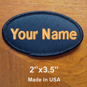 May include: Black oval patch with the text "Your Name" embroidered in orange thread. The patch measures 2 inches by 3.5 inches and is made in the USA.