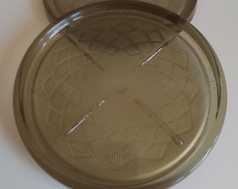 May include: Two brown glass coasters with a geometric pattern. The coasters are stacked on top of each other.