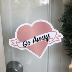 May include: A pink heart-shaped sticker with a white banner that says "Go Away".
