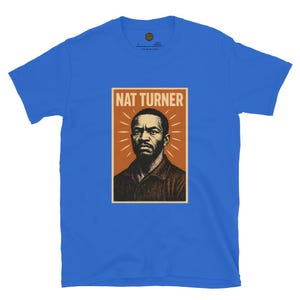 May include: Royal blue t-shirt featuring a portrait of Nat Turner. The portrait is set against a brown background with the name "NAT TURNER" in white block letters at the top. The design has a vintage, poster-like aesthetic.