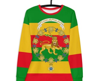 Può includere: Una felpa verde, gialla e rossa con un emblema di leone e corona sul davanti. L'emblema è circondato da un cerchio di croci e dal testo "እግዚአብሔር አምላክ ነው" in amarico.