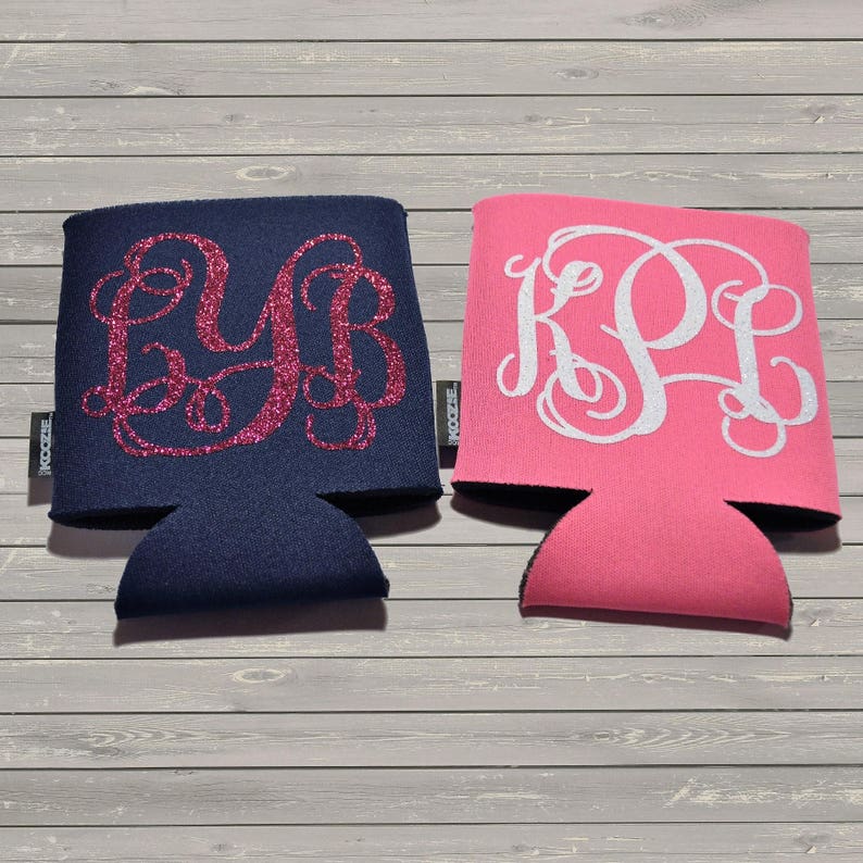 May include: Two personalized can coolers, one navy blue with pink glitter monogram "LYB" and one pink with white monogram "KPL".