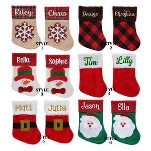 May include: Assorted Christmas stockings with personalized names like "Riley," "Chris," and "Denise." Styles include snowflake, snowman, and Santa designs. The stockings are red, green, and white, with various trim and fabric textures.