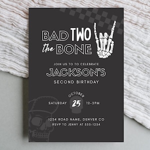 May include: Black invitation card with white text and graphics. The text reads "BAD TWO the BONE" and "JACKSON'S SECOND BIRTHDAY". A skeleton hand makes a rock-and-roll gesture. Includes date, time, and location.