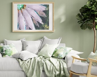 Puede incluir: Un sofá blanco con cojines y una manta verdes. Una impresión enmarcada de una flor rosa con hojas verdes cuelga de la pared detrás del sofá. Una planta verde está en la esquina de la habitación.