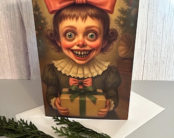 Puede incluir: Una tarjeta de felicitación con una ilustración vintage de una niña con un gran lazo rosa, sosteniendo una caja de regalo. La niña tiene una sonrisa amplia e inquietante y viste un vestido oscuro con cuello de encaje. Una ramita de vegetación está en primer plano.