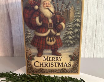 May include: A rectangular greeting card featuring an illustration of Santa Claus wearing a red plaid kilt and jacket, playing bagpipes while carrying a sack of gifts. The text Merry Christmas is printed at the bottom in dark brown lettering.