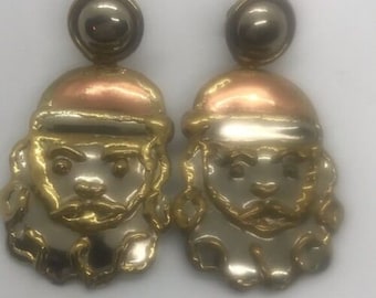 May include: A pair of dangle earrings featuring a gold and silver design of a face with a beard. The earrings have a copper colored top.