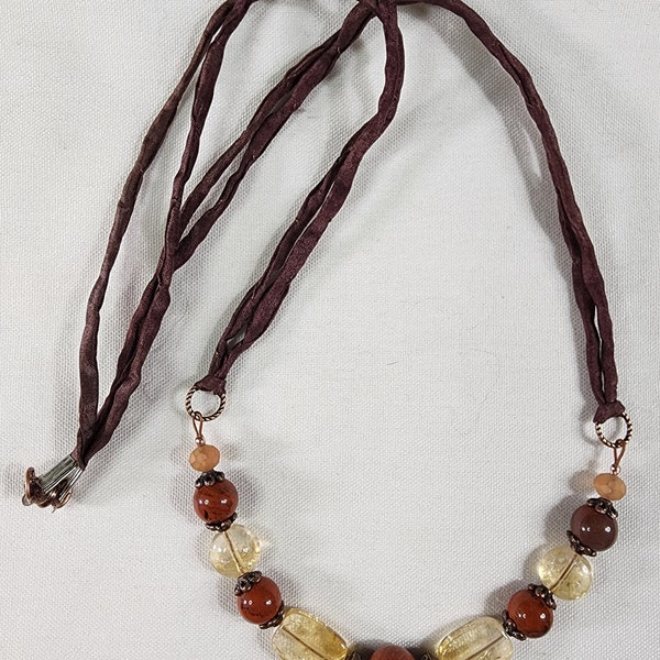 Silken Elegance is a stunning, yet delicate necklace of red jasper, citrine, and antique copper hanging from a strand of Chinese Silk cord.