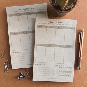 May include: Two weekly planner pages with a brown background. The top of each page has the text "Weekly Planner" and the months of the year listed. The pages are divided into days of the week, with spaces for writing notes and a habit tracker. The bottom of the page has the text "Desertdustdesign".