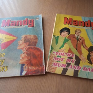 May include: Two vintage comic books with the title "Mandy" on the cover. The first comic features a colourful kite and the text "The Sky Sailors". The second comic features a group of people and the text "You're not my Mum and Dad!"