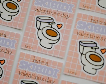 May include: A set of six pink and white Valentine's Day cards featuring a cartoon toilet with the text "have a SKIBIDI valentine's day" on each card.