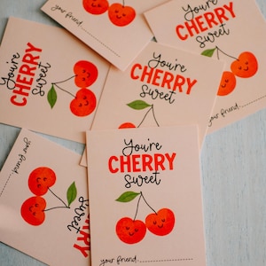 May include: Several light pink cards with the text "You're CHERRY Sweet" in red and black. Each card features a cartoon cherry illustration with a smiling face. The words "your friend" are printed at the bottom.