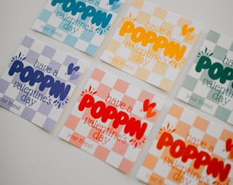 May include: Six colorful Valentine's Day cards with a checkered background. Each card has the text "have a POPPIN valentine's day" with a heart and a sunburst design. The cards are in different colors, including blue, yellow, green, red, and orange.