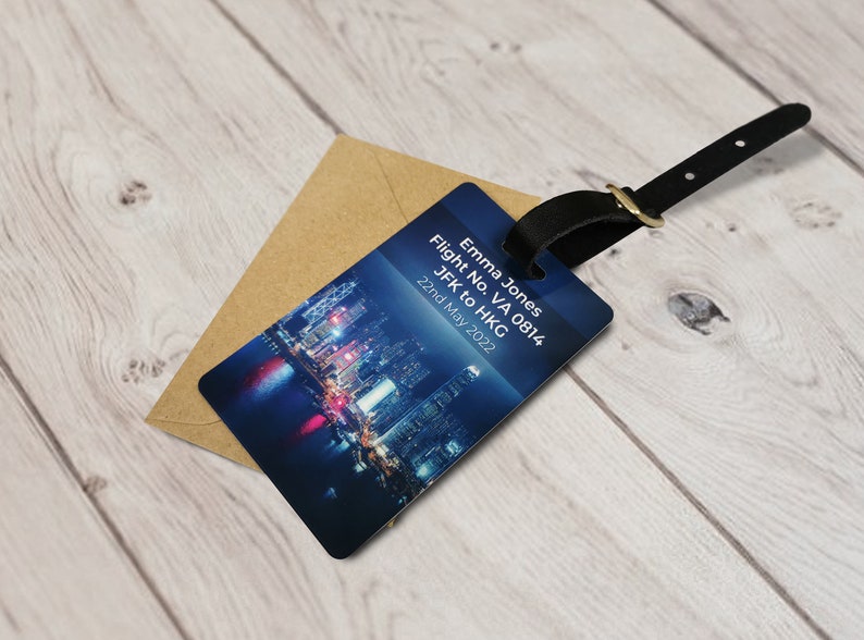 May include: A blue luggage tag with a cityscape image and the text "Emma Jones, Flight No. VA 0814, JFK to HKG, 22nd May 2022".