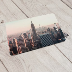 May include: A close-up view of a cityscape with tall buildings, including the Empire State Building, in the background. The city is bathed in a warm, golden light, creating a sense of vibrancy and energy.