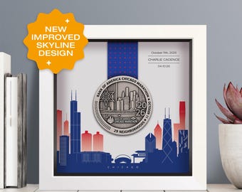 May include: A square white frame containing a Bank of America Chicago Marathon medal from 2026. The medal features a silver skyline design. The background displays a blue and red Chicago skyline graphic with the text October 11th, 2026, Charlie Cadence, and 04:10:26.