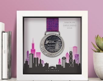 Może przedstawiać: Oprawiony medal Chicago Marathon z fioletową wstążką. Srebrny medal jest prezentowany w ramce z czarno-różową sylwetką panoramy miasta. Tekst na medalu brzmi "Chicago Marathon 10.13.2024".