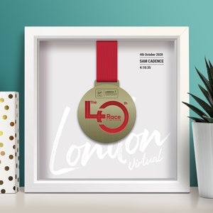 May include: A white framed picture with a gold medal inside. The medal is for the 40th London Marathon. The text on the medal reads "The 40th Race Finisher". The text on the frame reads "4th October 2020, SAM CADENCE, 4:10:35".