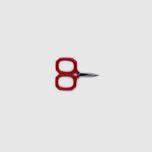 May include: Red metal scissors with a pointed tip. The handles are octagonal shaped.
