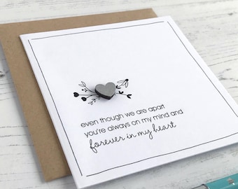May include: A white card with black text and a small silver heart. The text reads "even though we are apart you're always on my mind and forever in my heart".