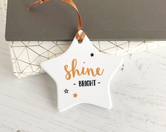 May include: White ceramic star ornament with gold lettering that reads "shine - bright -" and three black stars.