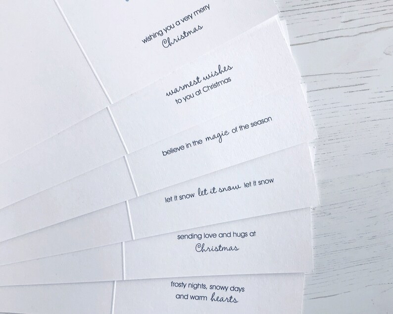 May include: A stack of white Christmas cards with various holiday greetings printed in dark blue ink. The messages include "wishing you a very merry Christmas" and "warmest wishes to you at Christmas."