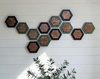 May include: A collection of eleven hexagonal wooden wall plaques arranged in a cluster. Each plaque features a natural wood grain center with a black or green painted frame and intricate black line art illustrations of various botanical plants.