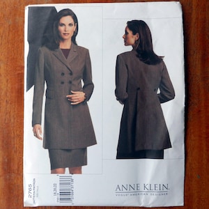 Puede incluir: Patrón de costura Anne Klein, Vogue American Designer. La imagen muestra a una mujer con un traje marrón con chaqueta cruzada y falda. El patrón es el 2765, con tallas 18, 20 y 22.