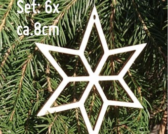 Op de afbeelding: Een set van zes houten sterornamenten, elk ongeveer 8 cm in diameter, met een geometrisch ontwerp. De ornamenten zijn wit en hangen tegen een achtergrond van groene dennennaalden. Tekst op de afbeelding luidt "Set: 6x ca. 8cm."