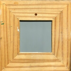 May include: Square wooden picture frame with a light brown finish. The frame has a layered design and a gray interior. A small nail is visible at the top center of the frame.