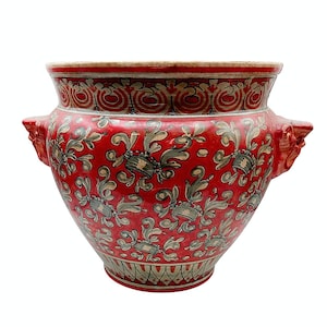 Può includere: Un vaso di ceramica rosso con elaborati disegni floreali e a volute in grigio e crema. Il vaso presenta due manici decorativi e un bordo dettagliato. Questo pezzo decorativo è adatto per uso interno o esterno.