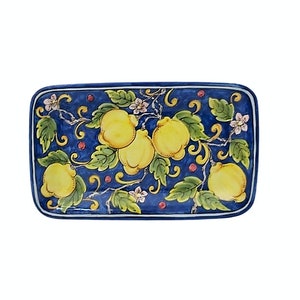 May include: Rectangular ceramic serving dish with a hand-painted design of yellow lemons, green leaves, and small pink flowers on a dark blue background. The dish has a white border.