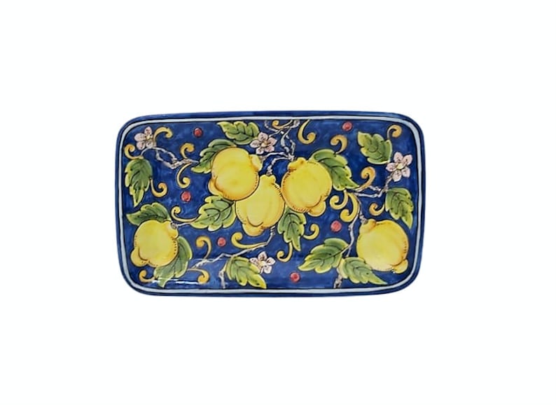 May include: Rectangular ceramic serving dish with a hand-painted design of yellow lemons, green leaves, and small pink flowers on a dark blue background. The dish has a white border.