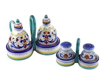 May include: A ceramic oil and vinegar set with matching salt and pepper shakers. The set features a colourful floral design with blue, yellow, and red accents. The oil and vinegar bottles have handles and are labelled "ACETO" and "OLIO".
