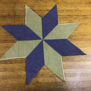 May include: A star-shaped patchwork quilt block with alternating yellow and blue gingham fabric.