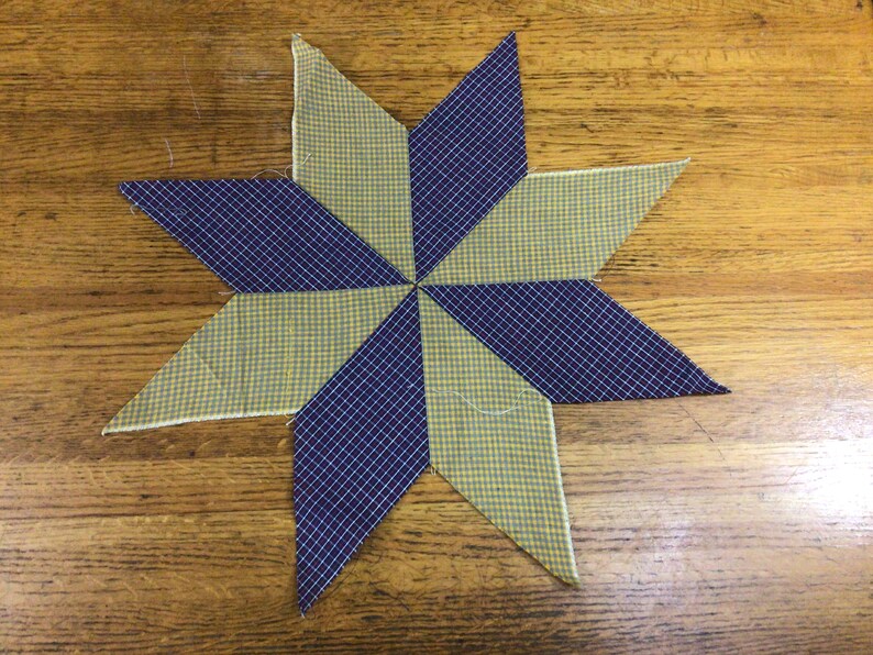 May include: A star-shaped patchwork quilt block with alternating yellow and blue gingham fabric.