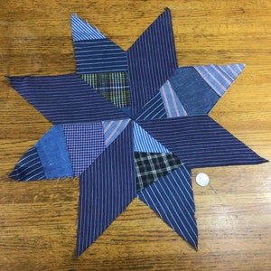 May include: A blue and white patchwork star made from fabric scraps. The star is made up of many different pieces of fabric, all sewn together to create a unique design.