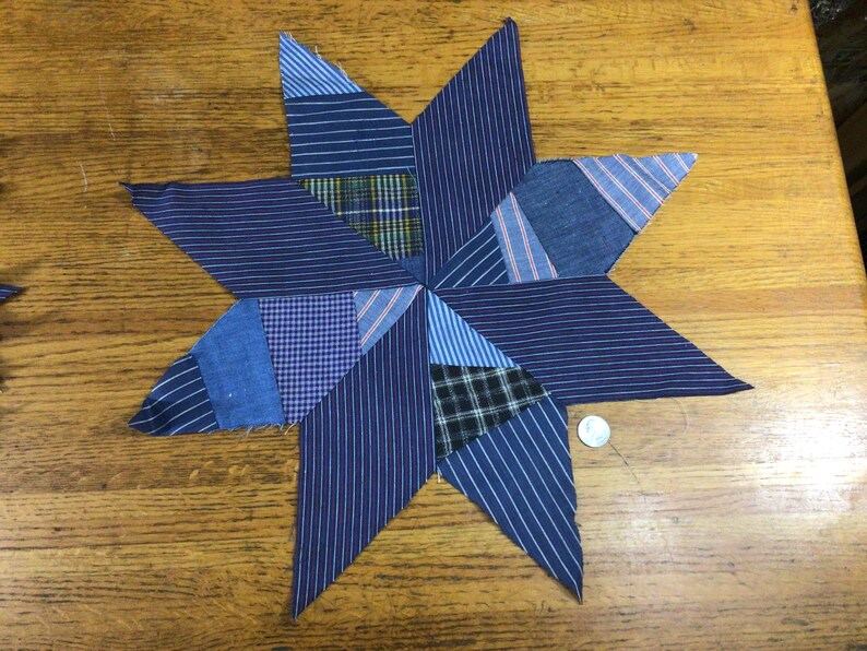 May include: A blue and white patchwork star made from fabric scraps. The star is made up of many different pieces of fabric, all sewn together to create a unique design.
