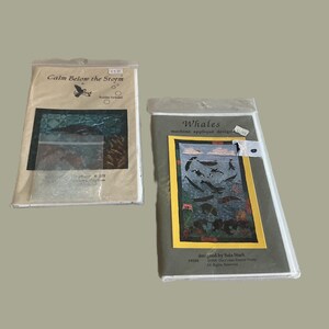 May include: Two packaged quilting patterns. One is titled "Calm Below the Storm" with a bird graphic. The other is titled "Whales" with a whale and ocean scene. Both are in clear plastic packaging.