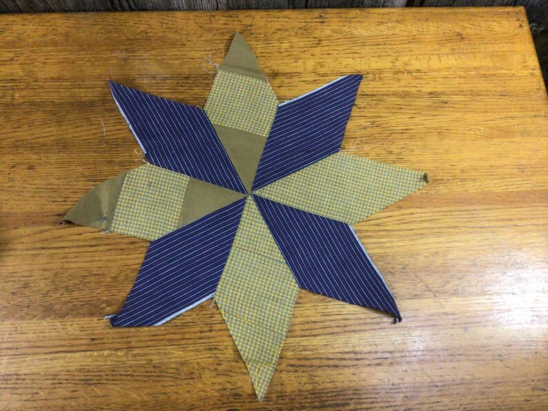May include: A handmade patchwork star quilt block with a blue and yellow plaid pattern. The block is made of eight triangles, each with a different pattern. The block is a traditional quilt pattern.